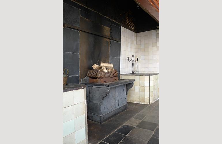 Stenen wandplaten in Oude keuken, de twee ijzeren platen op de grond en wand zijn omgedraaid, en er is een verhoogde vuurbak gebouwd.